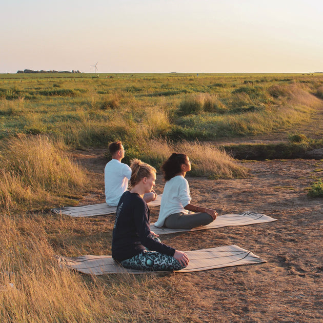 Man and woman meditating in a open field at sunsetTranquility and natural splendor with Nateea - Yoga and Safari - RETREAT - Zhoola