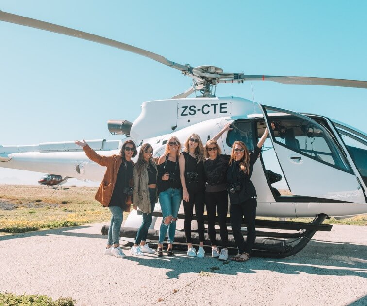 Women striking a pose in front of a helicopter - From the Beach to the Bush with Kiersten & Caity - VendorSafari & Exploration (Women only) - JOURNEY - Zhoola