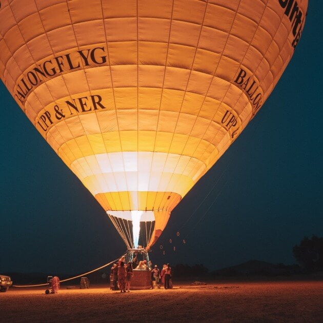 Girls enjoying a sunrise hot air balloon ride over a town during travel adventure"