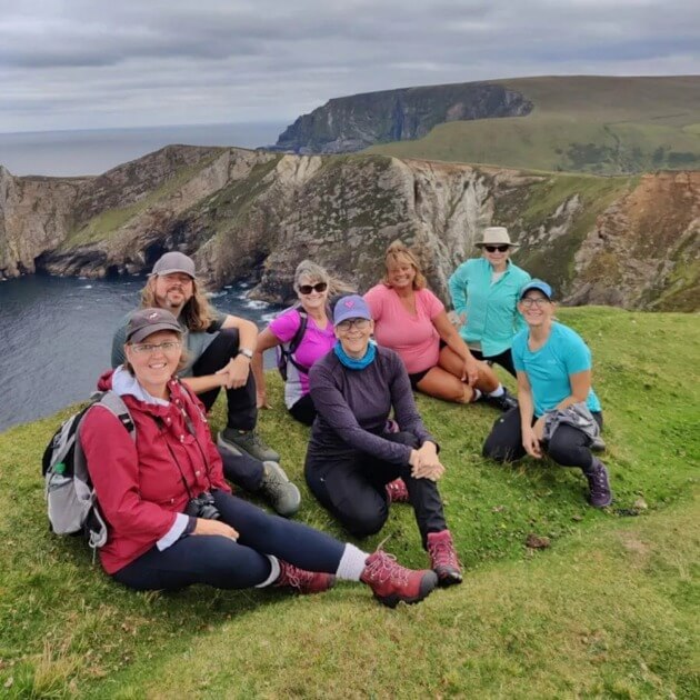 Happy traveler sitting on grass doing trekking in Ireland - People having fun in nature walking - Hike the Kerry way with Sherry Ott - VendorHike & Nature - JOURNEY - Zhoola