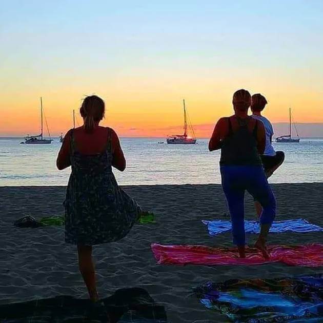An evening yoga class with participants in silhouette on a beach, with the ocean in the background . Back to your Roots at Nevis with Amanda Parr - VendorYoga & Scuba Diving - RETREAT - Zhoola